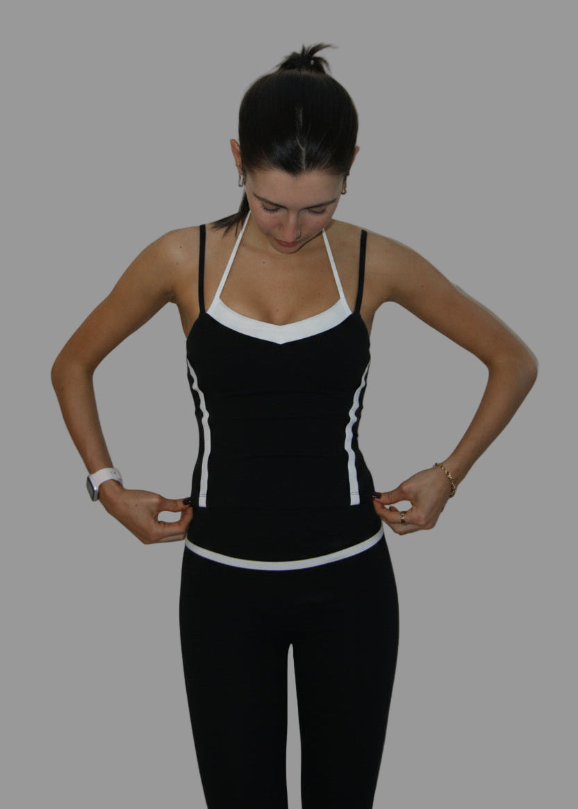 Woman wearing a black and white athletic outfit against a plain background